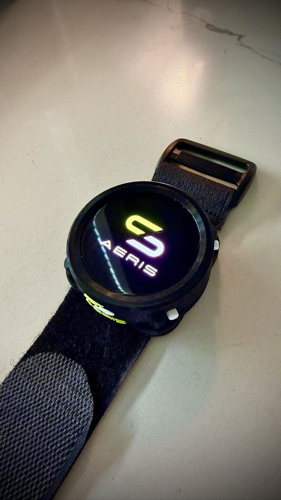 AERIS altimeter worn on wrist, screen lit with logo